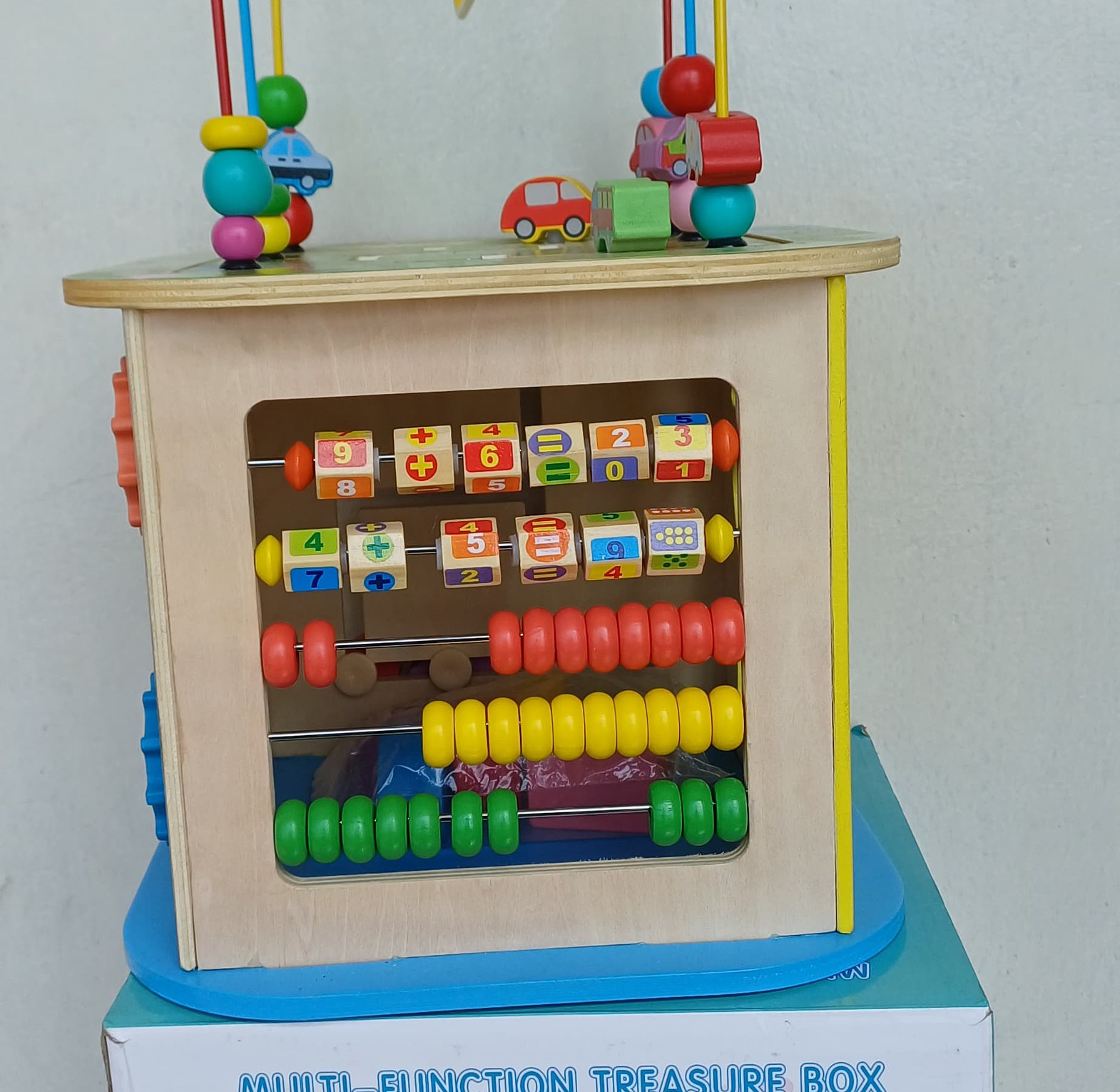 Wooden Activity Cube. With Several Activities, such as a bead maze on top, an abacus, a clock, shape sorters, and turning gears.  image